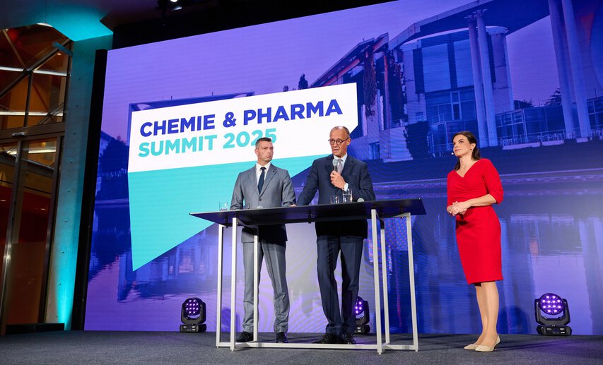 VCI-Präsident Markus Steilemann und Bundeskanzler Friedrich Merz auf dem Chemie & Pharma Summit 2025 in Berlin. Rechts im Bild: Moderatorin Isabelle Körner.
